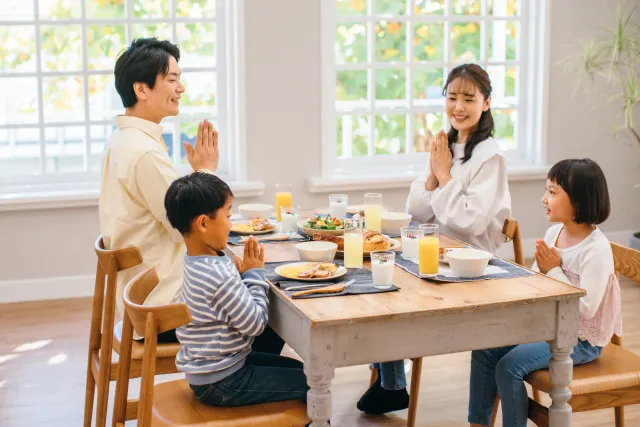 食事の挨拶をする家族の風景